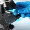 Microscope glass slides being placed for examination.